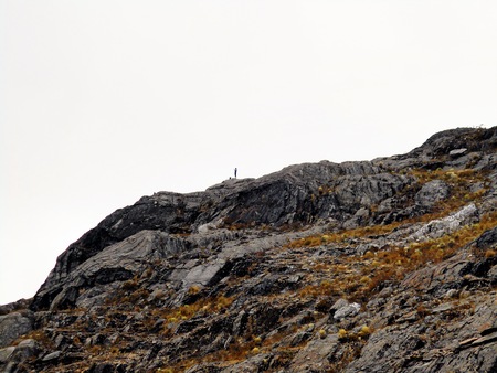 lonely photographer on hill being caught in the distance by another photographerの写真素材