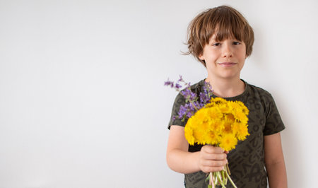 Smiling boy with wild flowers bunch on white background