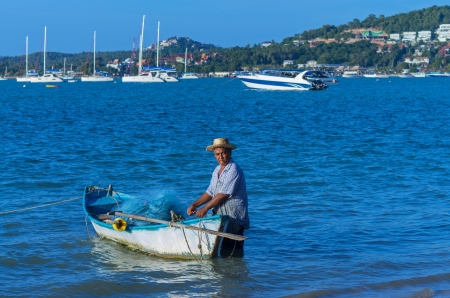 SAMUI, THAILAND - JUNE 29 Unidentified fisherman with small traditional boat on many yacht boats faraway background  on June 29, 2013 in SAMUI island, Thailand のeditorial素材