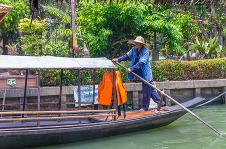 BANGKOK â APRIL 19: Undefined villager pading the traditional thai wooden boat at Klong Lat Mayom Float Market on April 19, 2014 in Bangkok. A traditional popular method of sightseeing in float market canals of Thailand.のeditorial素材