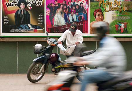 HOCHIMINH CITY, VIETNAM - NOV 24  An unidentified man is sitting and reading the newspaper on the bicycle in busy Hochiminh city traffic on November 24, 2007 in Hochiminh city, Vietnamのeditorial素材