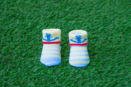 Handmade yellow and blue baby booties  on the grassの写真素材