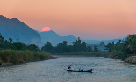Fisherman paddling rowboat to fishing when sunset, vangvieng, Laosの写真素材