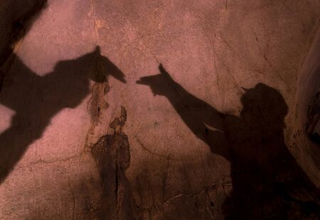 two hands forming a gun shadow on the wall in the caveの写真素材
