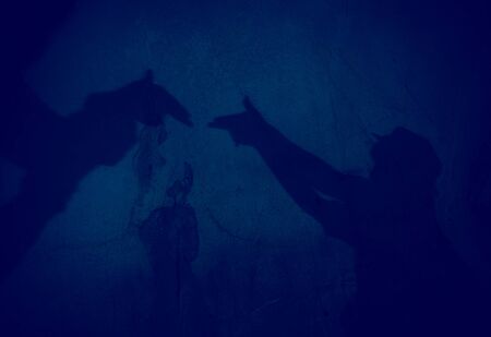 two hands forming a gun shadow on the wall in the caveの写真素材