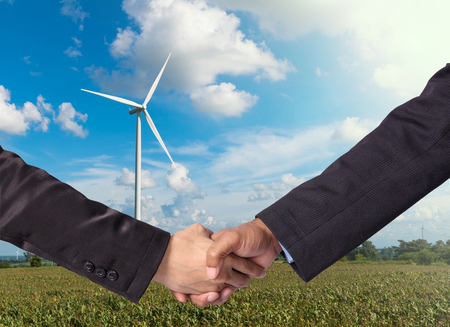 Hand shake between a businessman on Wind turbine power generator backgroundの写真素材
