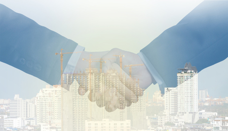 double exposure handshake between businessman on a construction building backgroundの写真素材