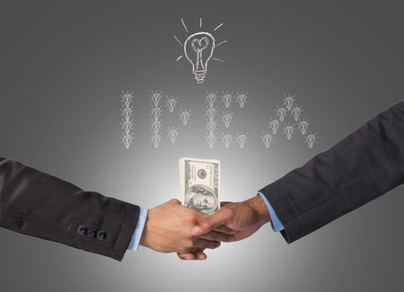 Hand shake between a businessman with dollar money for idea of successの写真素材