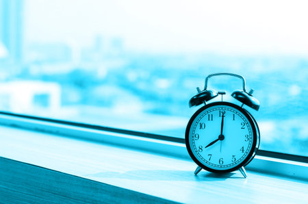 Vintage alarm clock at windows at early morning