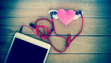 Portable audio earphones with tablets and heart Crochet on wood background, vintage color toneの写真素材