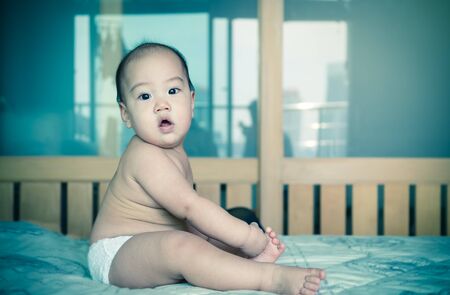 Portrait of happy asian baby on the bedの写真素材