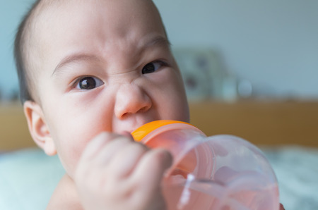 Closeup Asian baby drinking water on the bedの写真素材
