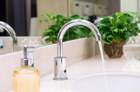 Chrome faucet with washbasin in modern bathroom Chrome faucet with washbasin in modern bathroom