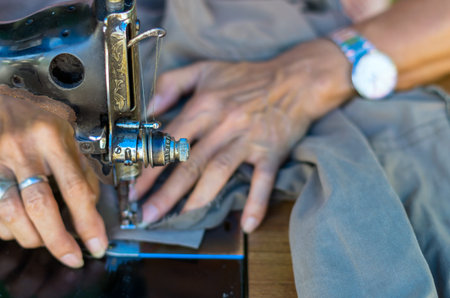 The vintage sewing machine on hand of fashion designer blur background, black and white toneの写真素材