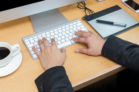 Businessman working at Workplace with computer, tablet, smart phone, key board and coffee cup on wooden tableの写真素材