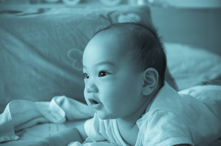 Portrait of happy asian baby on the bedの写真素材