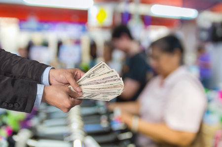 Businessman offered the money on the Abstract blurred photo of store blur with customer choose product bokeh backgroundの写真素材