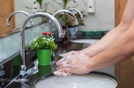 Hand washing with Chrome faucet over the washbasin in modern bathroom