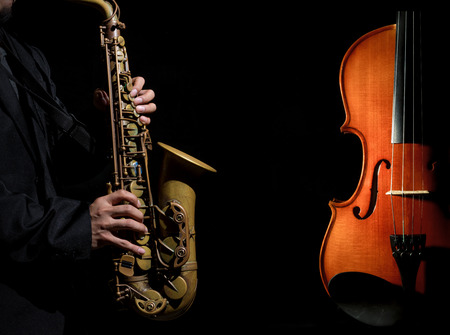 Closeup saxophone in player action with Violin orchestra musical instruments on black backgroundの写真素材