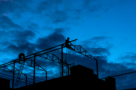 silhouette of Carpenter working on top of the roof structureの写真素材