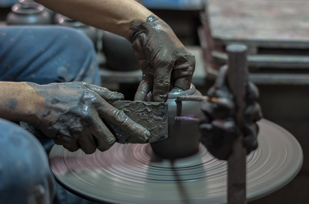 closeup hands of a potter, creating an earthen jar on the traditional machine, low lightの写真素材