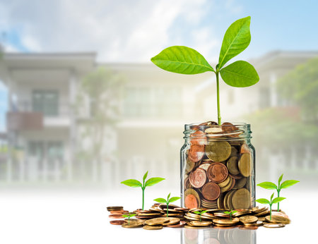 Gold coins and seed in clear bottle on photo blurred house background,Business investment growth...