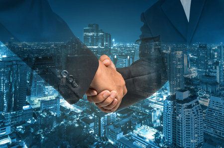 Double exposure handshake between businessman on cityscape background, Business concept