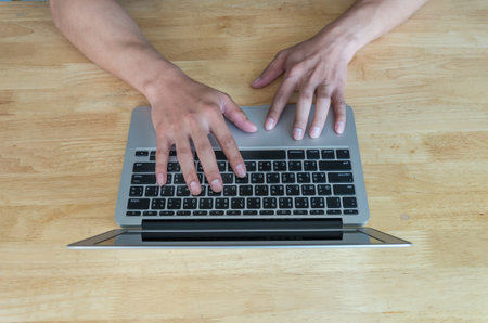 Top view of hand using the laptop on the wooden table, business concept, english and thai text on...