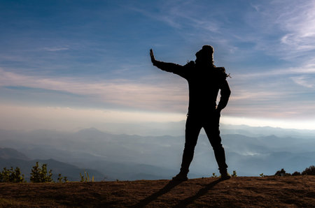 silhouette of a man who show hand reject over the mountains landscape