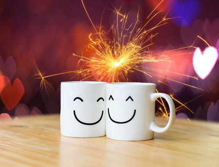 Two happy cups on Electric sparklers with heart bokeh background, valentine love conceptの写真素材