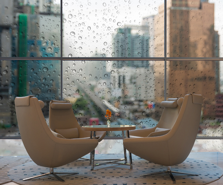 Lobby area of a hotel which can see abstract Blurred photo of sky train with cityscape and construct with Rain drop On the Glass from top viewのeditorial素材