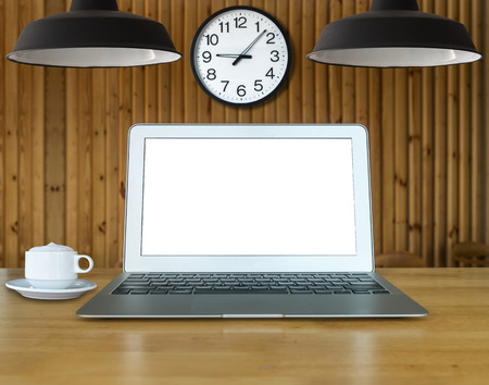 Workspace with laptop and coffee cup on the wooden table with wooden wall background and vintage lighting and clockの写真素材