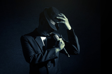 Songer hand holding the microphone and singing on black background, musical conceptの写真素材