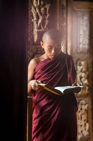 Buddhist novice standing and reading at Shwenandaw pagoda, mandalay, myanmarの写真素材