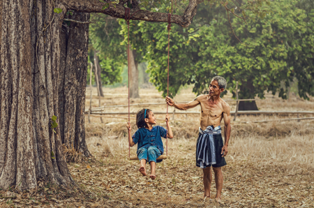 Asian old man and girl are playing the traditional countryside swing on nature background,Countryside Lifestyle conceptの写真素材