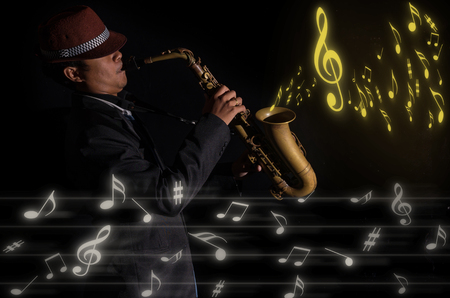 A saxophone player in a dark background with music melody, musical conceptの写真素材