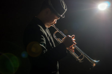 Musician playing the Trumpet with spot light and len flare on the stage