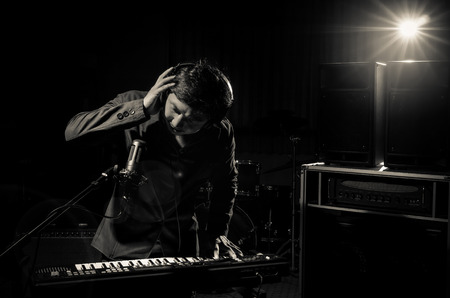 Musician playing keyboard with music instrument and lens flare from spot light on dark background, Musician conceptの写真素材