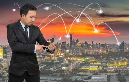 Asian businessman calling mobile phone with network connection on cityscape background, Business connection conceptの写真素材