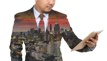 Double exposure of businessman using the tablet with cityscape on blurred building background, Business invest conceptの写真素材