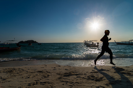 silhouette of running at sunrise time over the sea beach with lens flareの写真素材