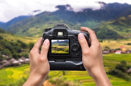 Hands holding the camera which taking photo of Rice fields on terraced of Mu Cang Chai District at sunrise time, YenBai province, Northwest Vietnam, worm toneの写真素材