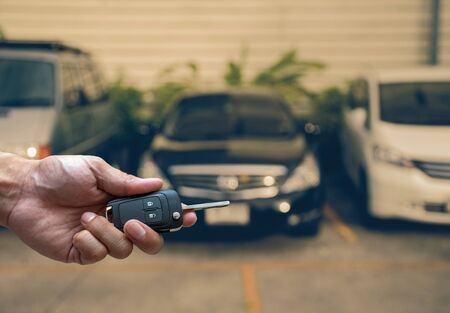 Hand holding and touching the keys over photo blurred of used car for open the door car,...