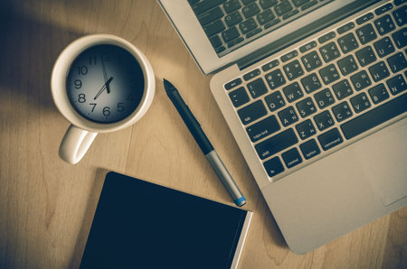 Top view of Laptop, notepad and coffee cup which shown time over surface wooden background,flat lay