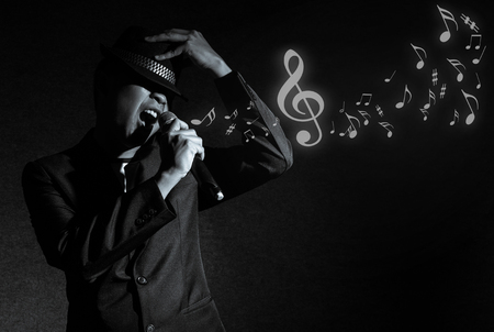 Songer hand holding the microphone and singing with music notes on black background, musical conceptの写真素材