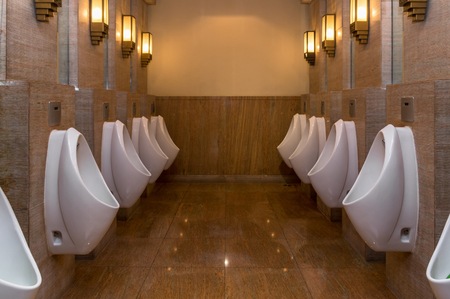 row of white urinals in men's luxury toilet, worm color tone, low lightの写真素材