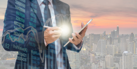 Double exposure of businessman using the tablet with Stock market chart on Network connection line between building over the top view of cityscape background, Business Trading and connection conceptの写真素材