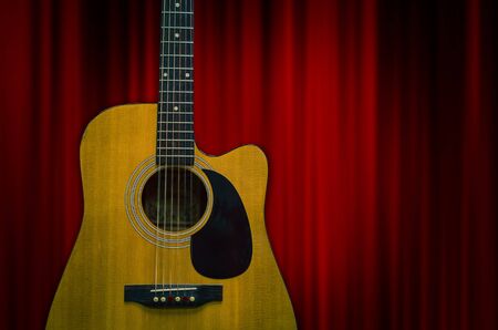 Guitar over the red curtain background, musical concept
