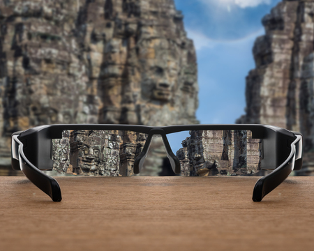 Conceptual image of Stone face focused in glasses lenses over the photo blurred of Stone face of...