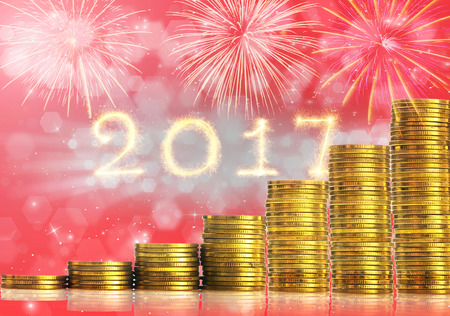 stacks of gold coins step with Happy new year 2017 written with Sparkle firework over the Abstract photo of christmas and fireworks background, investment and celebrate with greeting cards conceptの写真素材